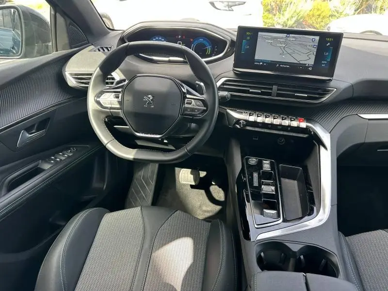 Vue intérieure avant du Peugeot 3008 Hybride Rechargeable 2024, montrant le volant cuir multifonction et l'écran tactile central.
