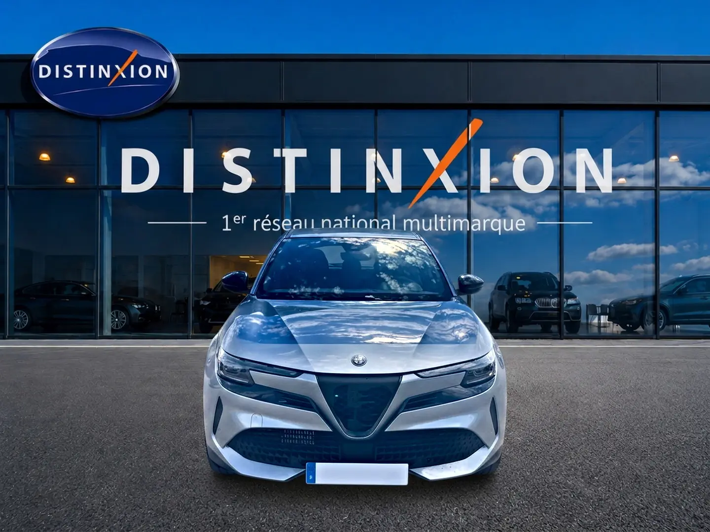Vue frontale d'une Alfa Romeo Junior 1.2 hybride grise, avec calandre triangulaire caractéristique et phares LED.