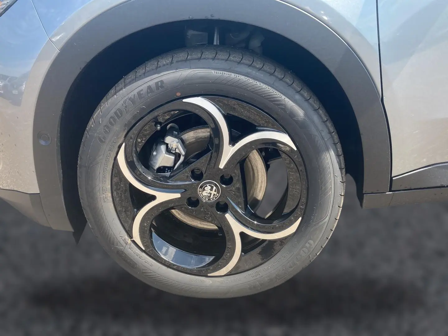Gros plan sur la jante en alliage noire et argentée de l'Alfa Romeo Junior gris, avec logo Alfa Romeo au centre.