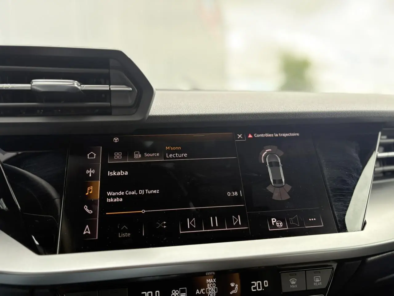 Vue rapprochée de l'écran central tactile de l'Audi A3 Berline gris 2020, affichant la lecture musicale et l'assistance au stationnement.