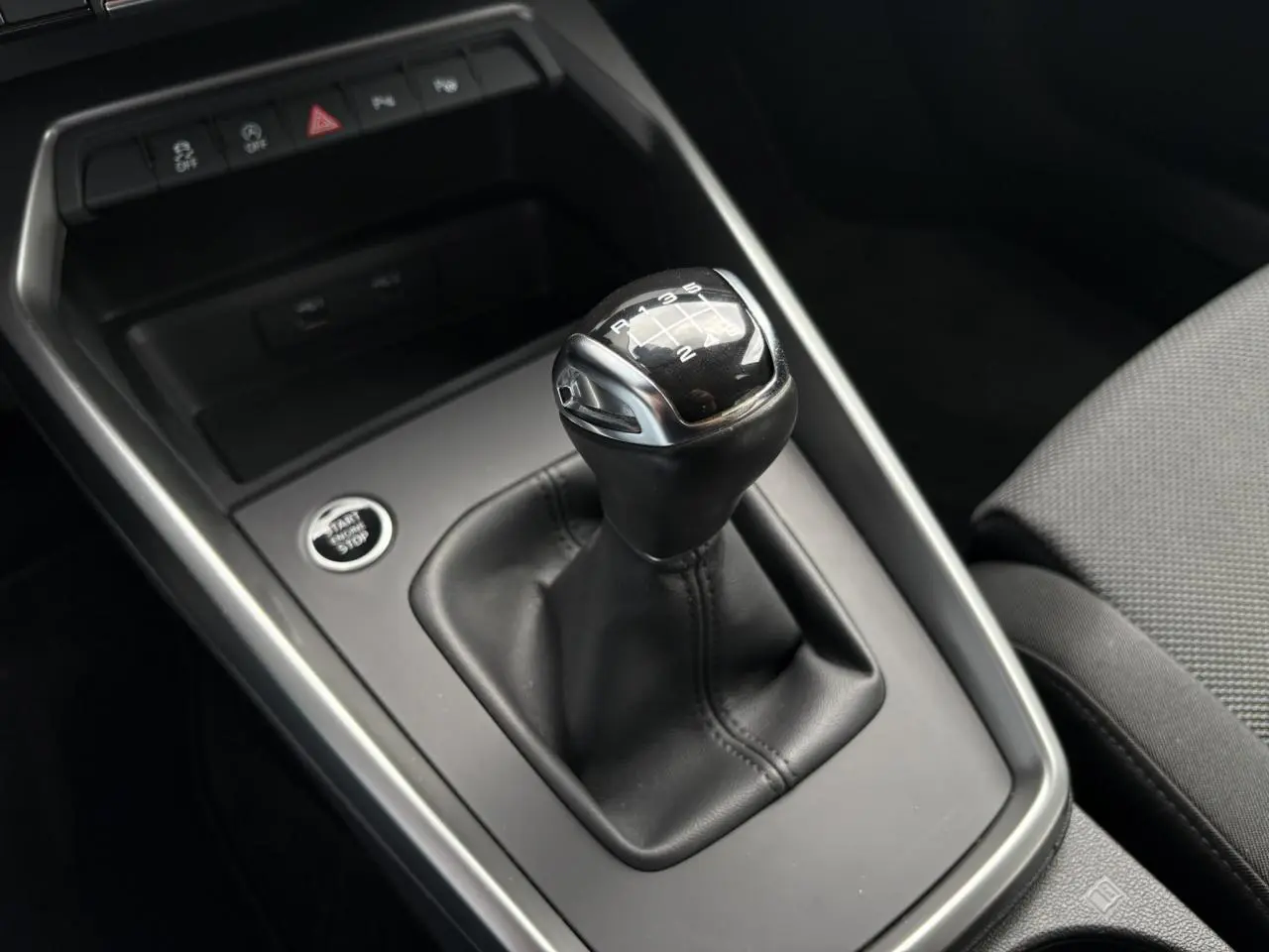 Gros plan sur le levier de vitesse manuelle noir et argenté de l'Audi A3 Berline 35 TFSI gris, avec bouton start/stop visible.