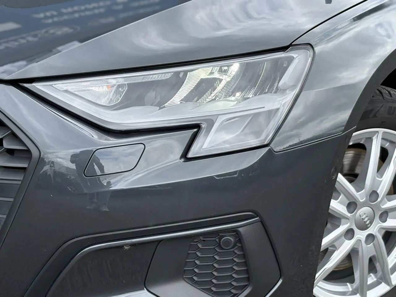 Gros plan sur le phare avant droit gris métallisé d'une Audi A3 Berline 35 TFSI 2020 avec jante alu visible.