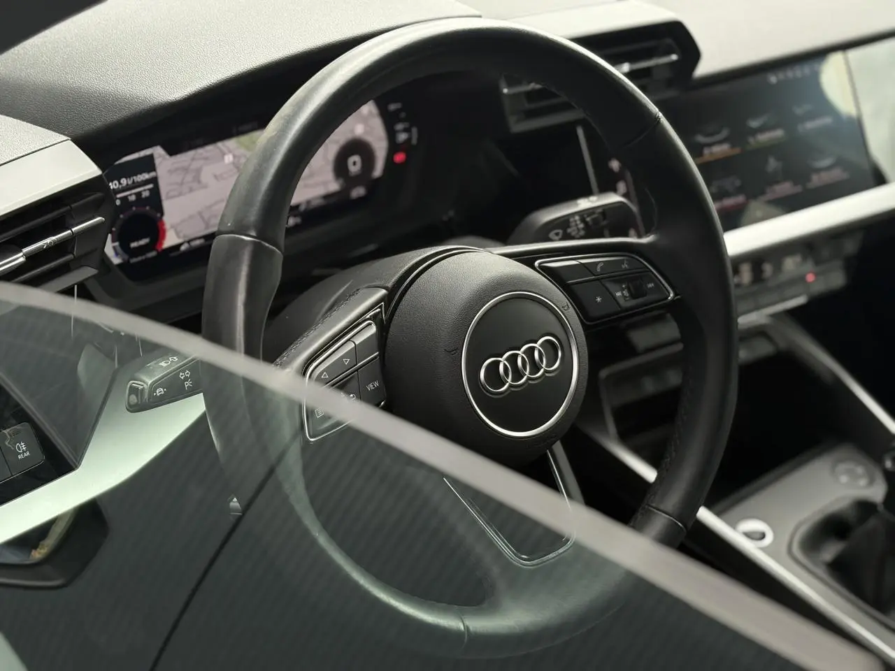 Vue rapprochée du volant cuir noir multifonctions de l’Audi A3 Berline 35 TFSI 150 Design 2020 avec tableau de bord numérique.