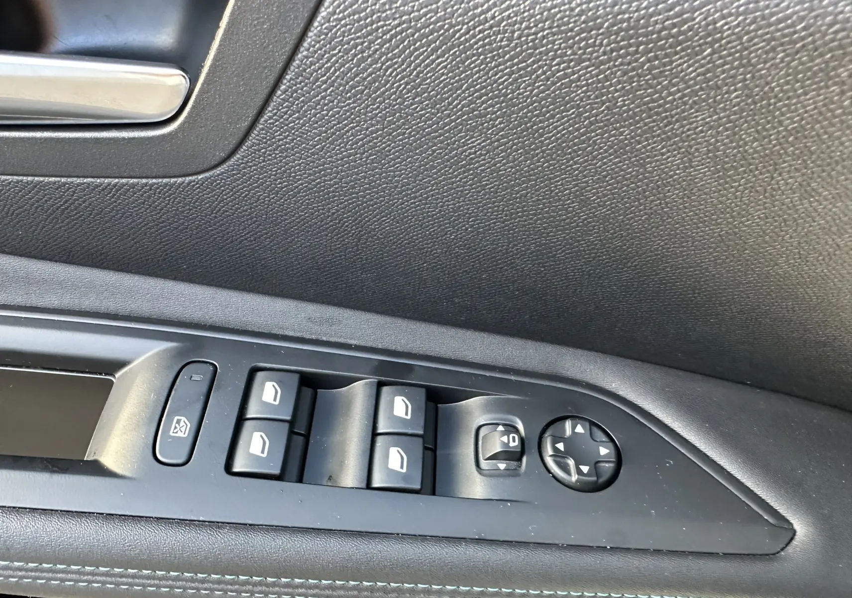 Détail des commandes des vitres et des rétroviseurs sur la portière côté gauche d'un Peugeot 3008 blanc nacré 2024.