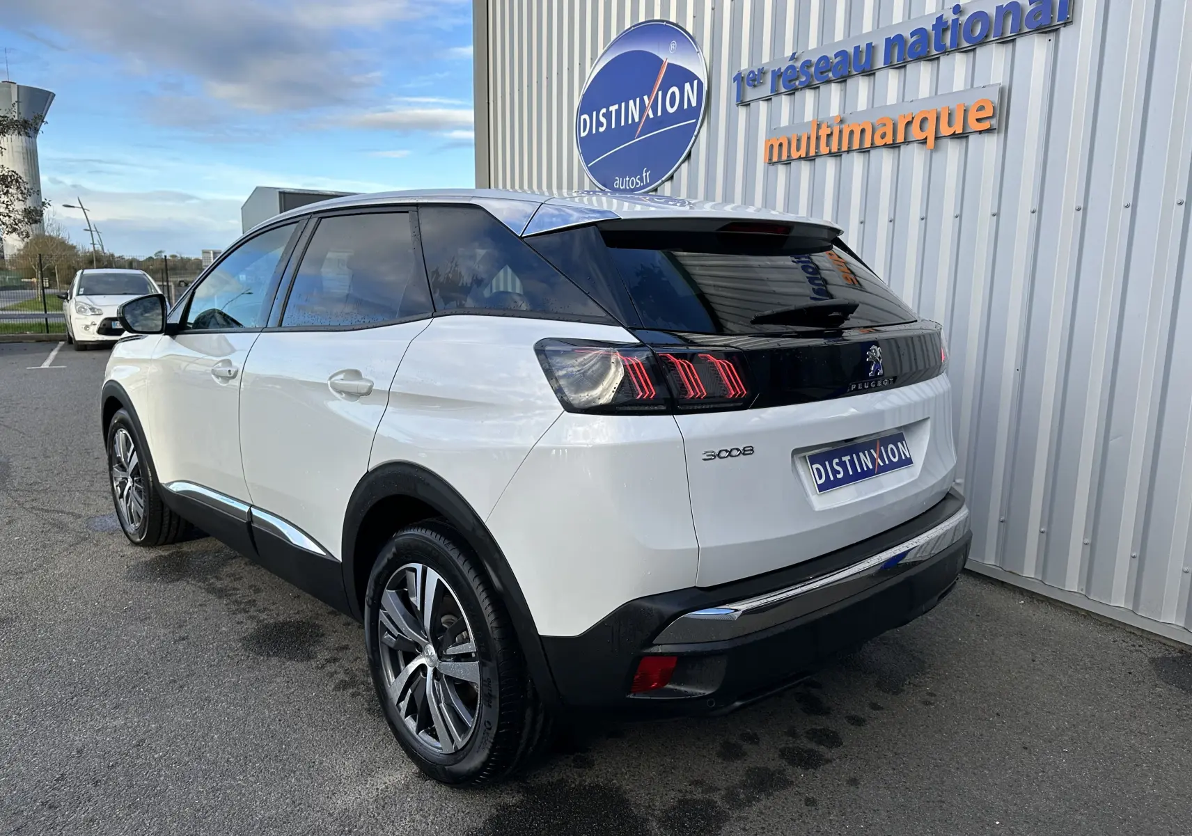 Peugeot 3008 blanc nacré vu en 3/4 arrière droit, avec feux arrière à griffes et toit noir brillant.