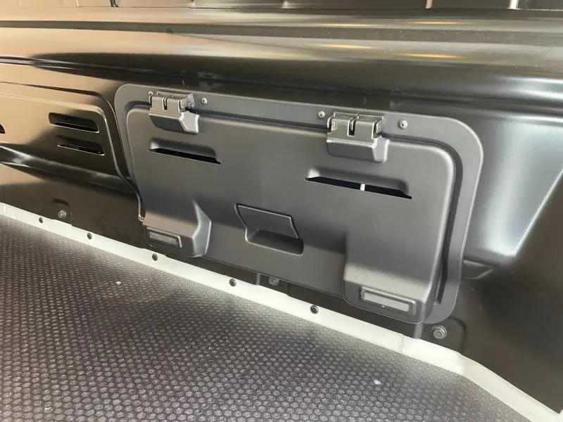 Gros plan sur la cloison complète tôlée noire avec trappe du Renault Trafic Fourgon blanc Glacier, intérieur espace de chargement.