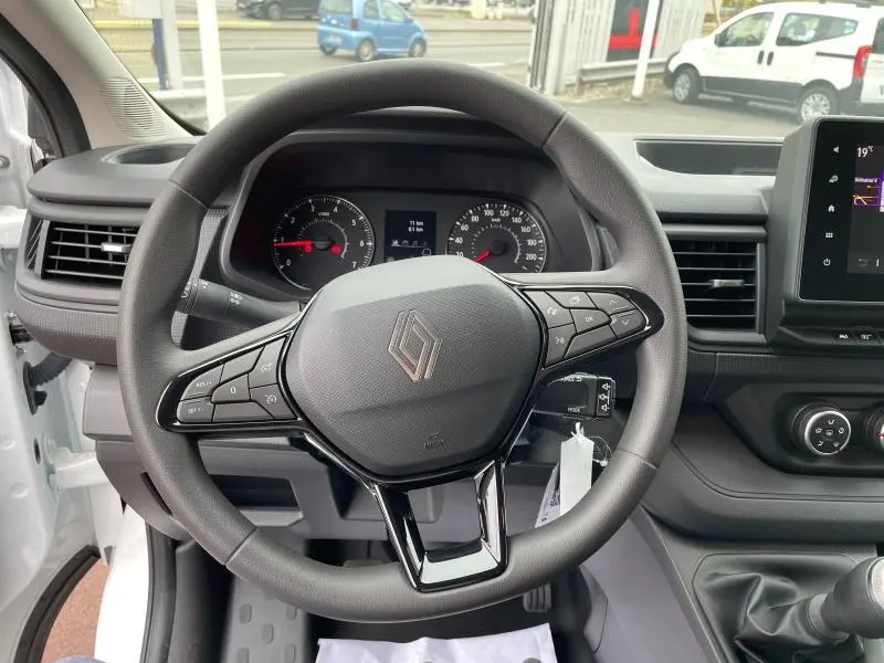 Vue intérieure centrée sur le volant noir du Renault Trafic Fourgon blanc, avec tableau de bord et écran tactile visibles