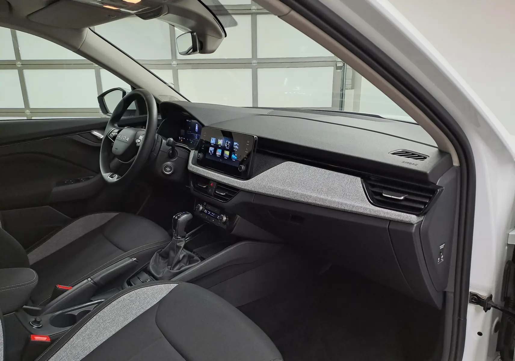 Vue intérieure côté conducteur du Skoda Kamiq blanc Lune 2025, avec tableau de bord moderne et écran tactile central.