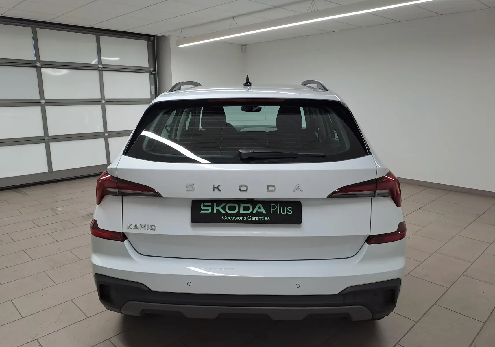 Vue arrière d’un Skoda Kamiq blanc Lune 2025 avec feux arrière distinctifs et radars de stationnement visibles.