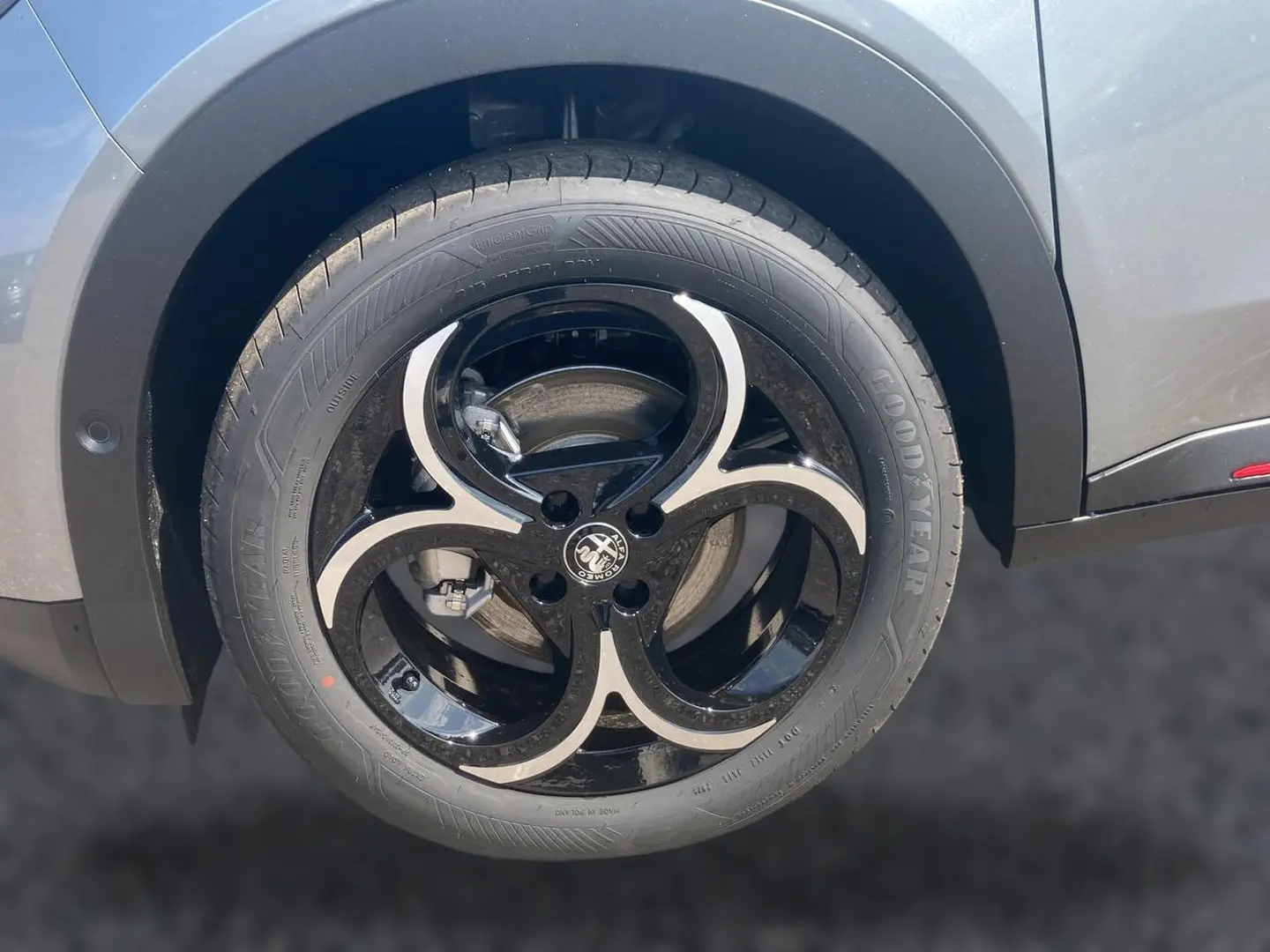 Gros plan sur la jante alliage noire et argentée côté droit de l'Alfa Romeo Junior gris t/noir, mettant en valeur le logo central.