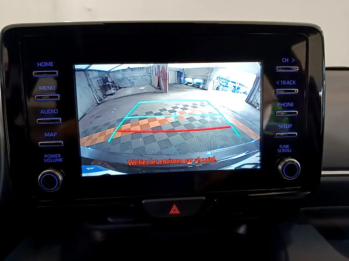 Écran tactile central de la Toyota Yaris hybride 2021 montrant la caméra de recul avec lignes de guidage colorées.
