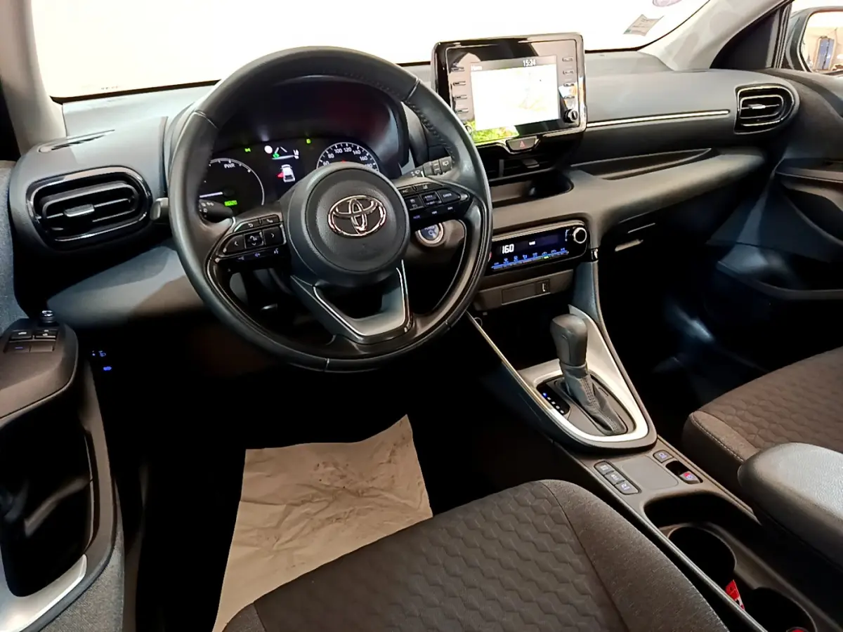 Intérieur noir de la Toyota Yaris Hybride 2021 vu côté conducteur, avec volant multifonctions et écran tactile central.
