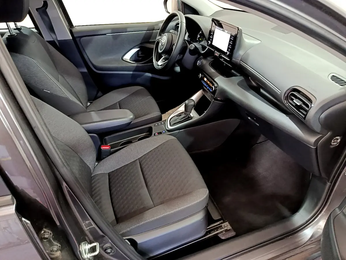 Intérieur avant droit de la Toyota Yaris hybride 2021, sièges gris foncé et tableau de bord avec écran tactile central.