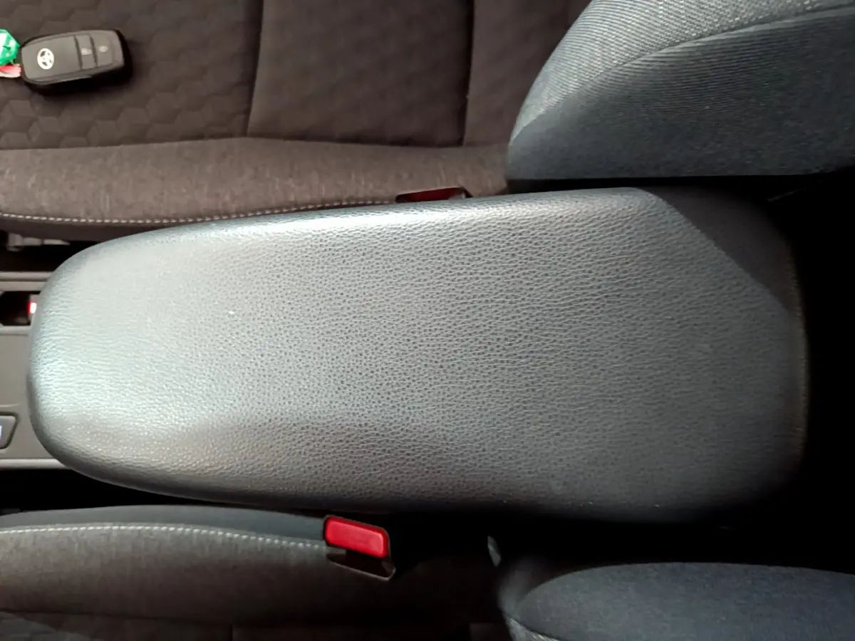 Vue rapprochée de l'accoudoir central gris foncé de la Toyota Yaris hybride 2021 avec clé posée sur le siège adjacent.