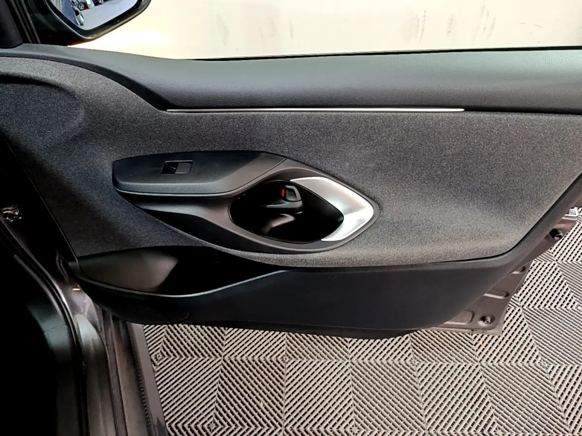 Gros plan sur la porte côté gauche intérieure noire de la Toyota Yaris hybride 2021, avec poignée argentée et tissu gris.