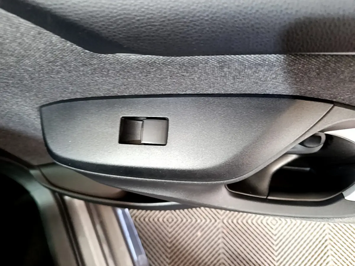 Détail de la poignée intérieure côté gauche de la Toyota Yaris hybride gris clair, avec bouton de verrouillage intégré.