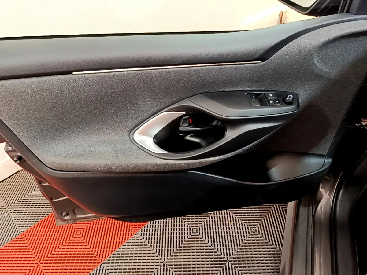 Vue côté gauche de la porte intérieure grise de la Toyota Yaris hybride 2021 avec commandes de vitres et poignée argentée.