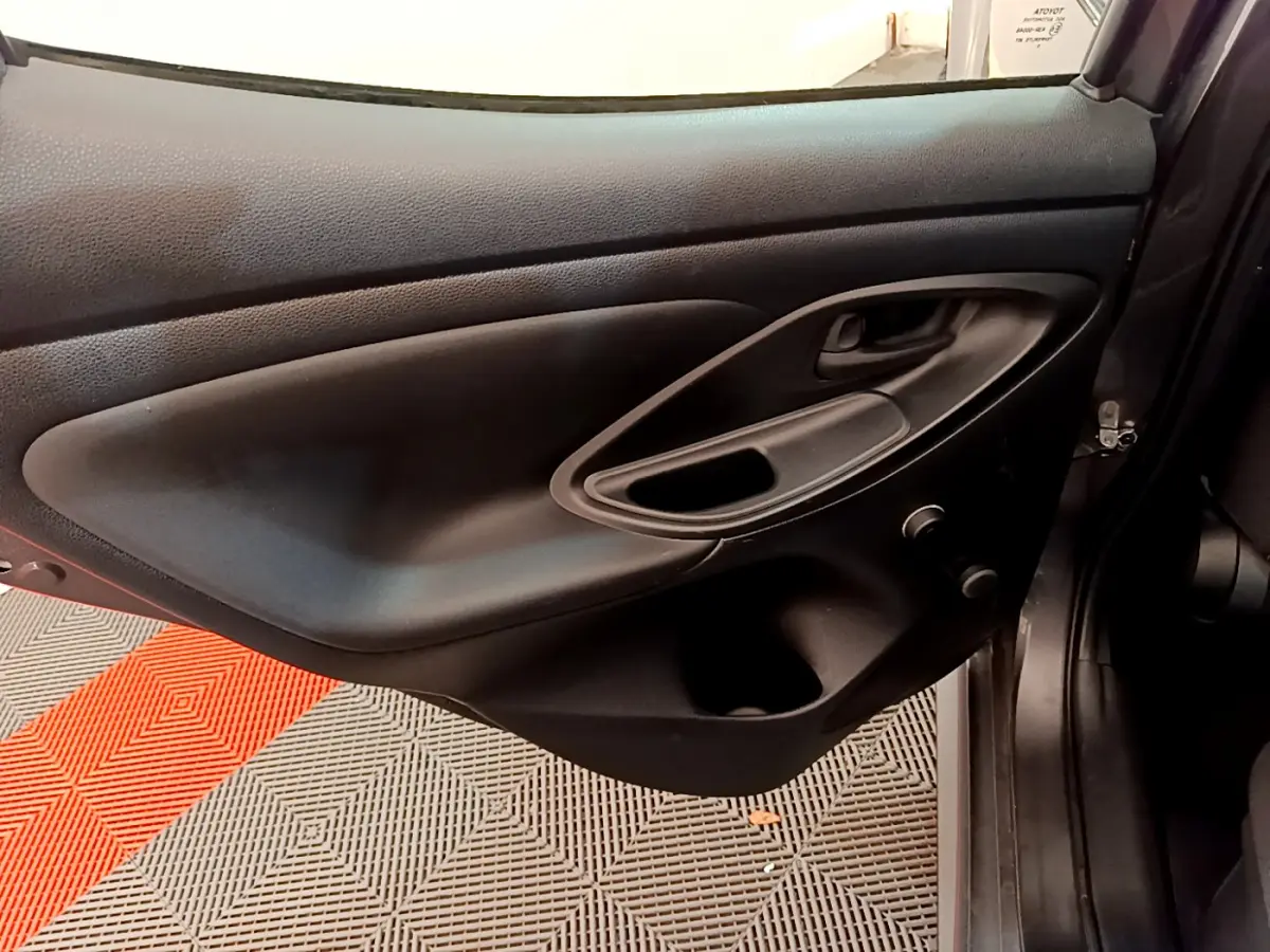 Porte intérieure côté gauche de Toyota Yaris hybride 2021, en plastique noir avec poignée intégrée et rangement.