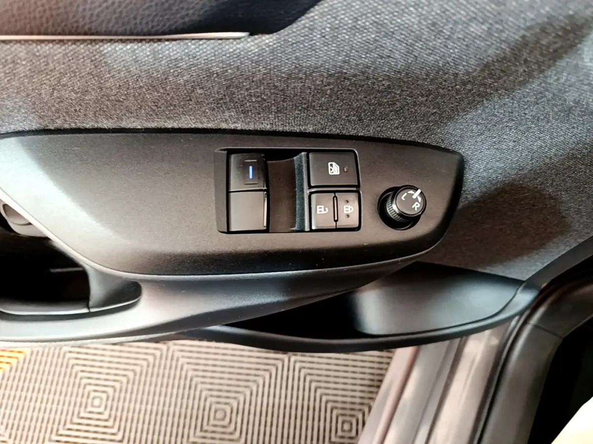 Vue rapprochée des commandes de réglage des rétroviseurs et des vitres côté conducteur d'une Toyota Yaris hybride gris clair 2021.