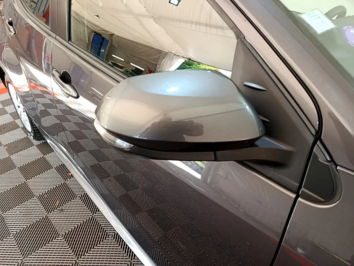 Rétroviseur côté droit gris clair de la Toyota Yaris Hybride 116h 2021 avec poignée de porte visible en reflet.