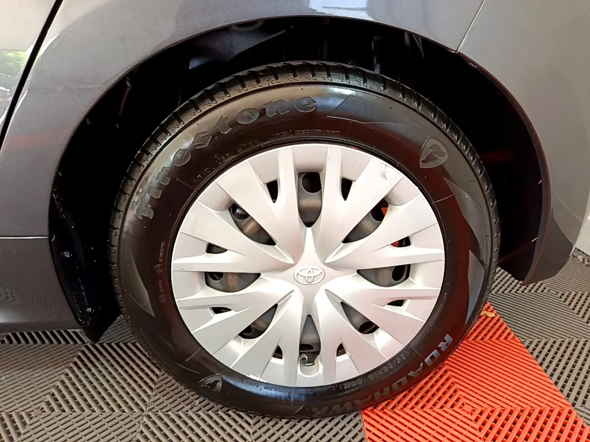 Gros plan sur la roue avant gauche grise de la Toyota Yaris hybride avec enjoliveur argenté et pneu Firestone.