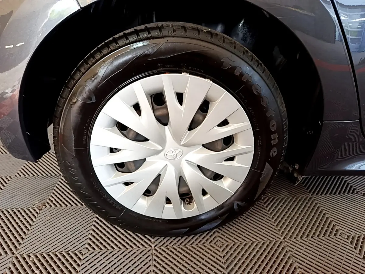 Gros plan sur la roue avant droite grise d'une Toyota Yaris hybride 2021 avec enjoliveur Toyota et pneu Firestone.