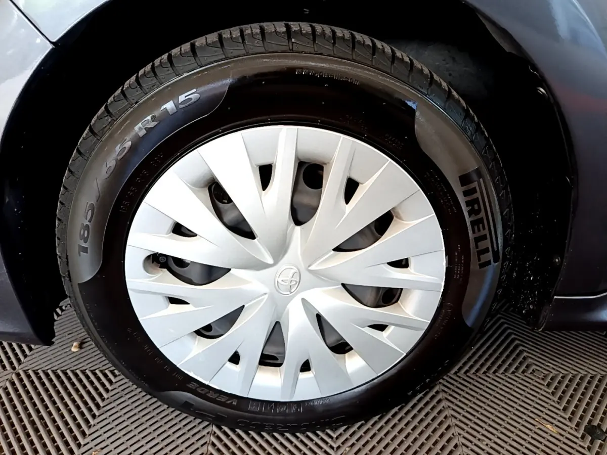 Gros plan sur la roue avant gauche grise d'une Toyota Yaris hybride avec enjoliveur blanc et pneu Pirelli.