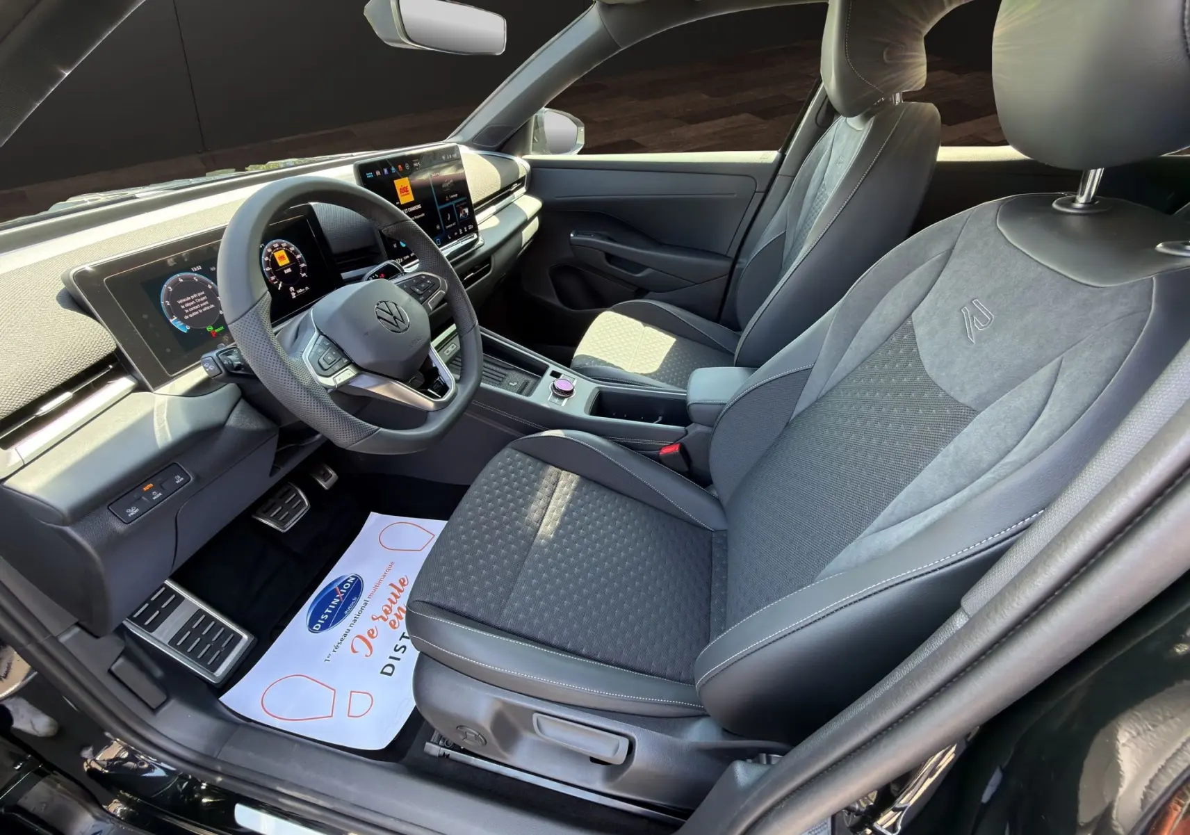 Vue intérieure côté conducteur du Volkswagen T-Roc noir ébène 2026, mettant en valeur le tableau de bord numérique et les sièges R-Line en tissu et cuir.