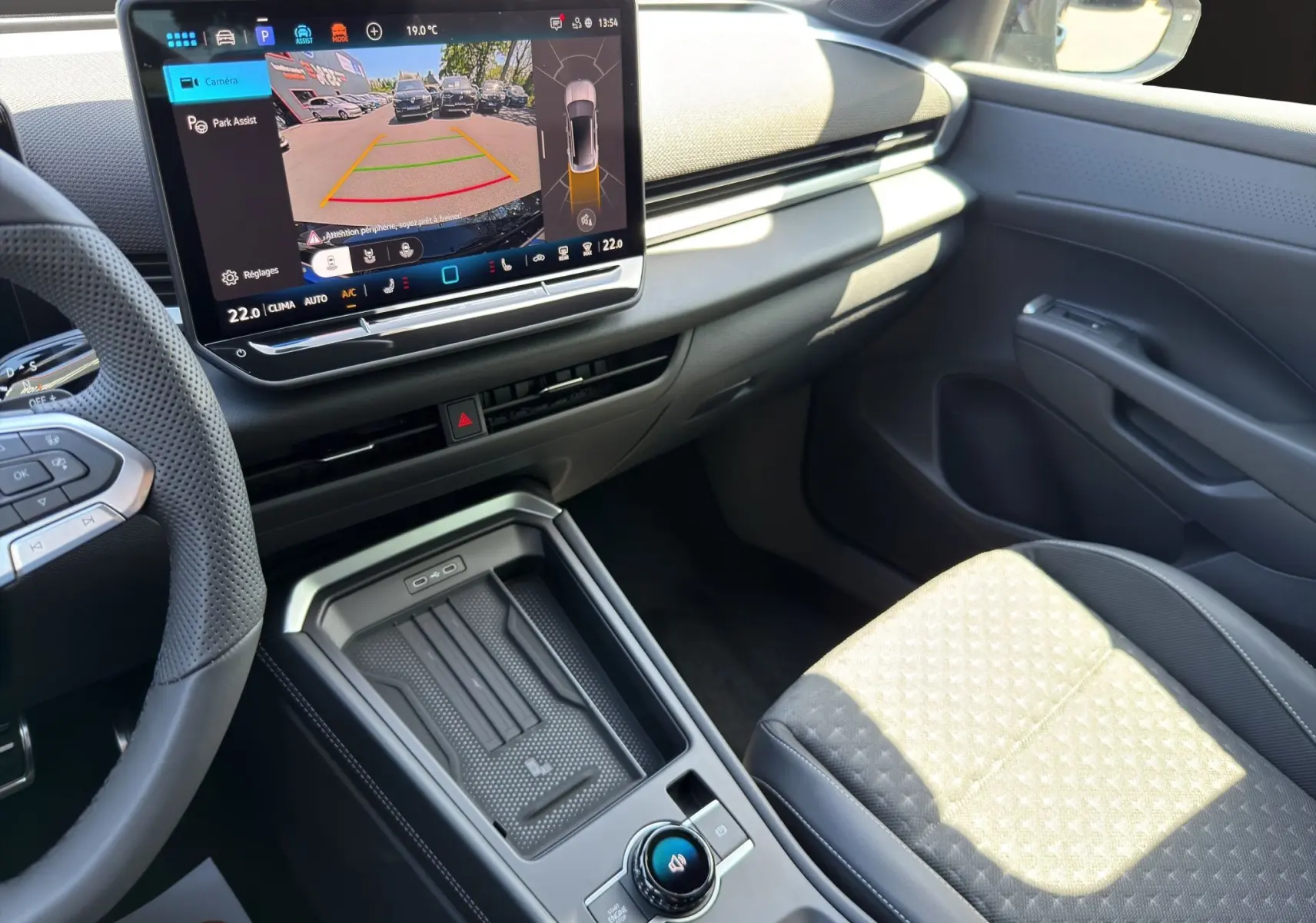 Vue intérieure côté passager du Volkswagen T-Roc 2026 noir ébène, avec écran tactile affichant la caméra de recul et console centrale moderne.