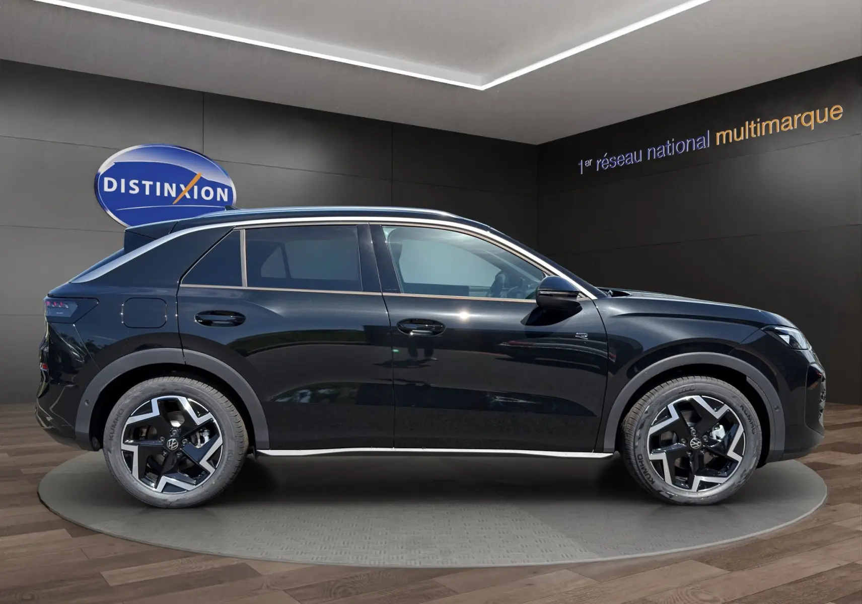 Vue de profil côté gauche du Volkswagen T-Roc noir ébène 2026 R-Line avec jantes bi-ton et attelage visible.