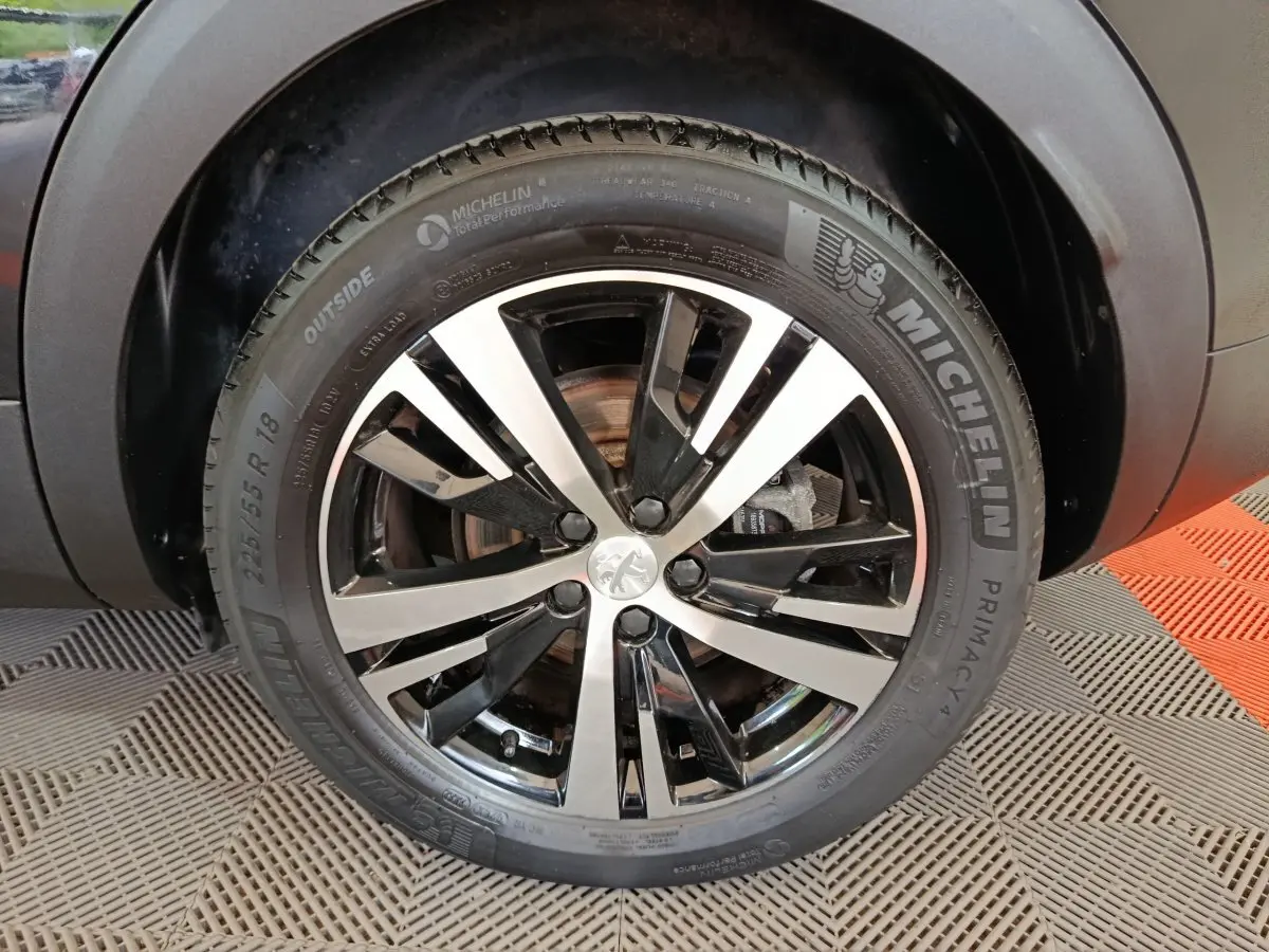 Gros plan sur la roue avant droite du Peugeot 3008 noir, avec jante alliage bicolore et pneu Michelin.