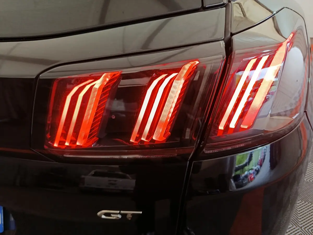 Gros plan sur les feux arrière rouges du côté gauche d’un Peugeot 3008 noir version GT.