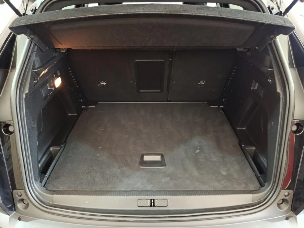 Coffre ouvert vu de l'arrière d'un Peugeot 3008 noir, montrant un espace de chargement propre et spacieux.