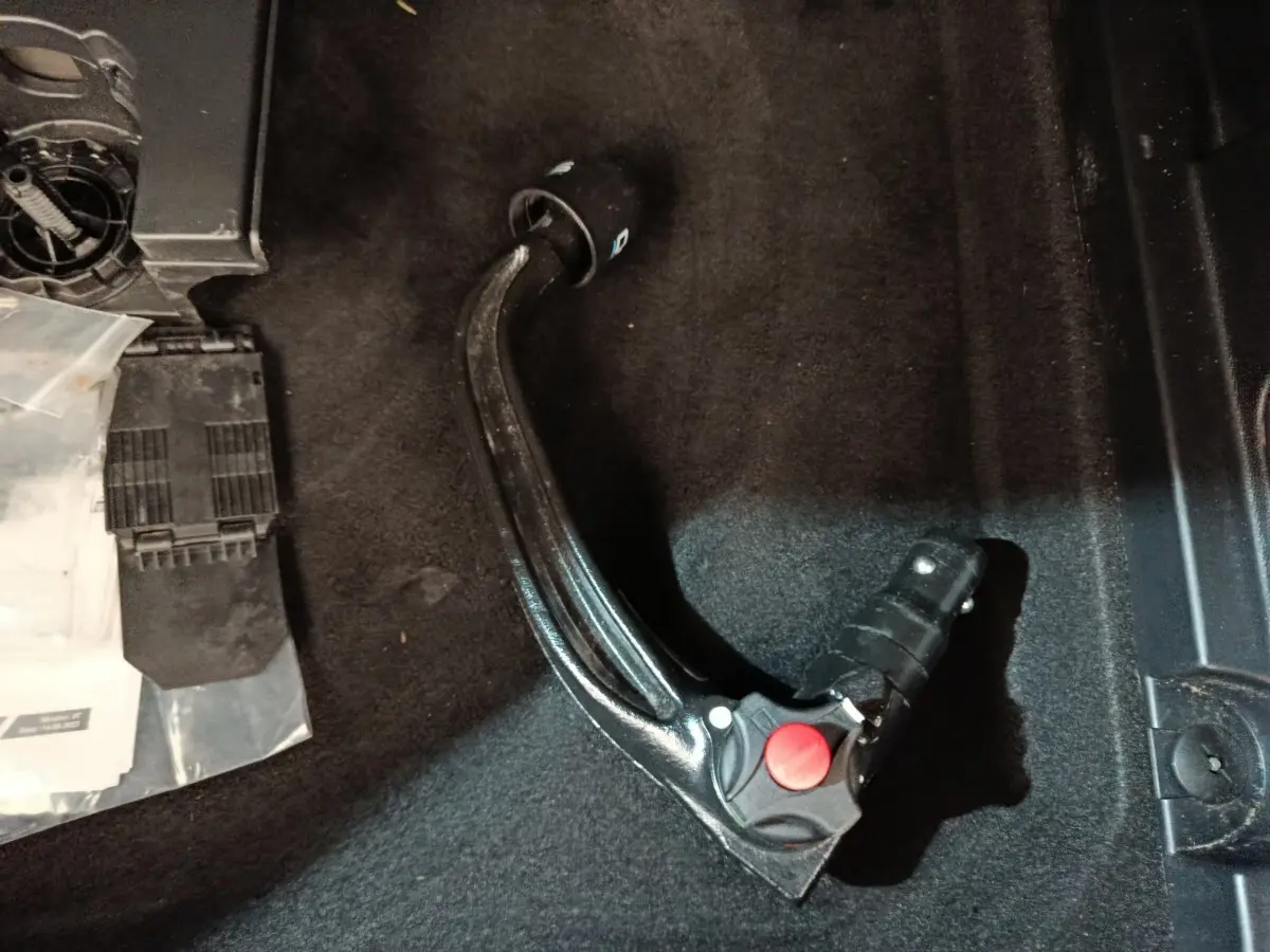 Gros plan sur l'attelage de remorque noir posé sur le tapis intérieur du coffre d'un Peugeot 3008 noir.