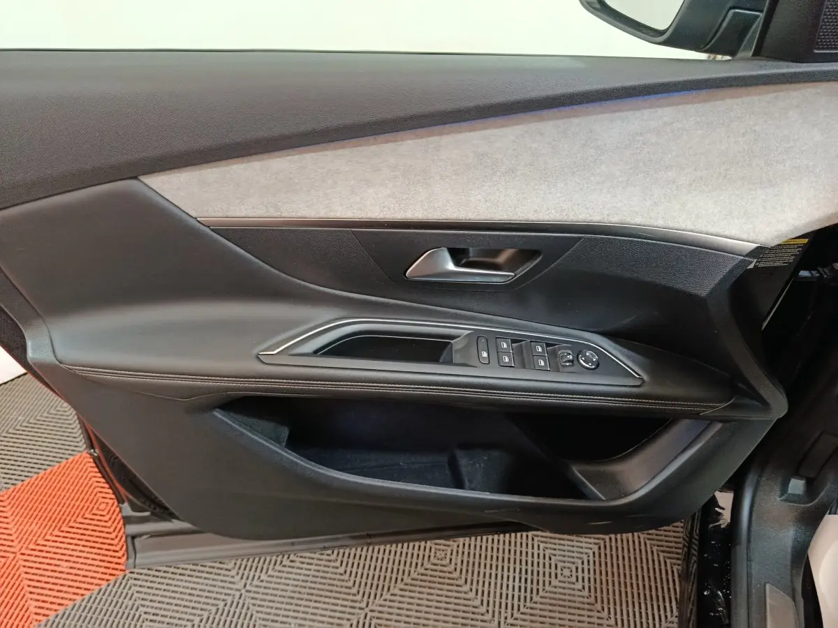 Vue intérieure côté gauche de la porte avant noire du Peugeot 3008 avec commandes des vitres et poignée intégrée.