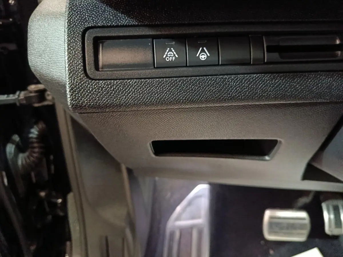 Vue rapprochée des commandes d’aide à la conduite sous le tableau de bord du Peugeot 3008 noir, version GT 2022.