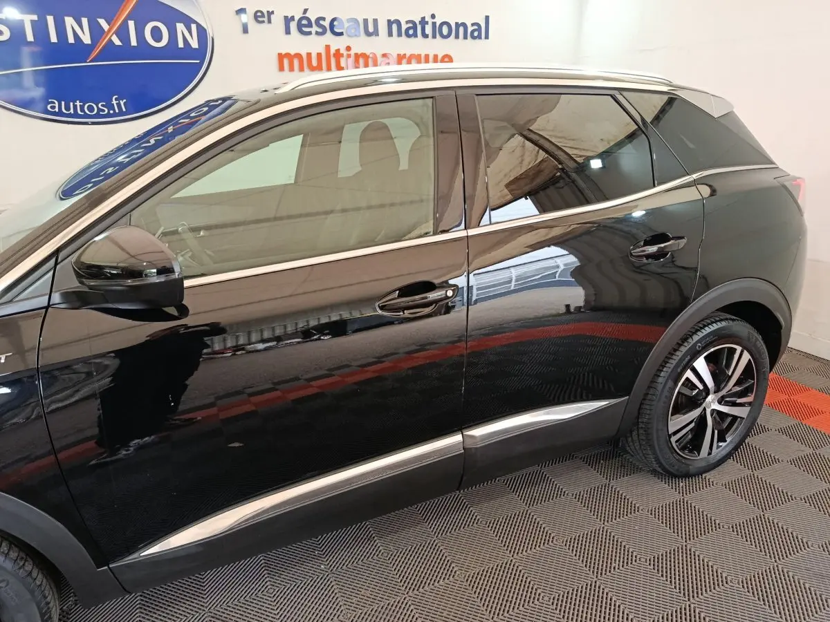 Vue latérale gauche d’un Peugeot 3008 noir 2022 avec jantes alliage et barres de toit chromées visibles.
