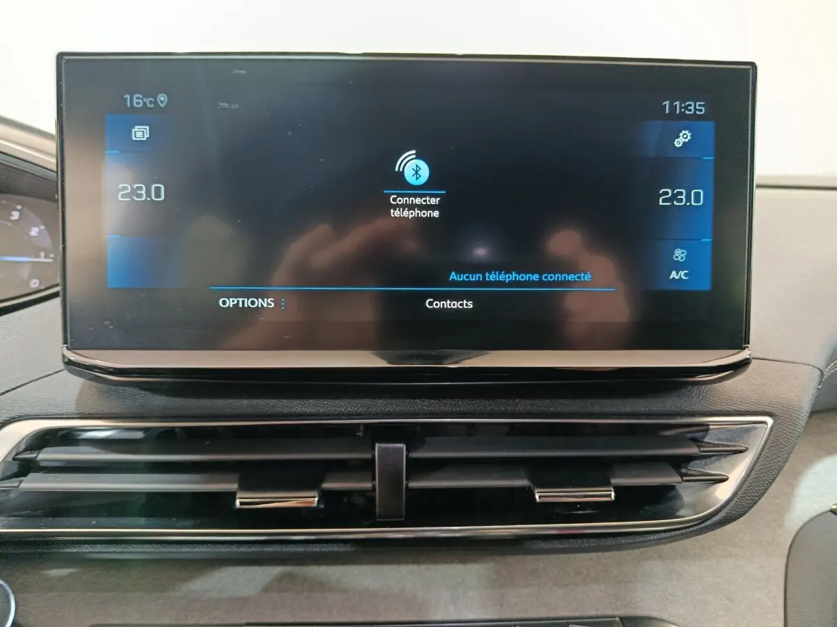 Écran tactile central du tableau de bord du Peugeot 3008 noir, affichant la connexion Bluetooth et la climatisation à 23°C.
