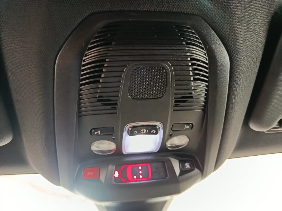 Vue en contre-plongée du plafonnier noir du Peugeot 3008 GT 2022 avec éclairage et boutons de commande rouges.