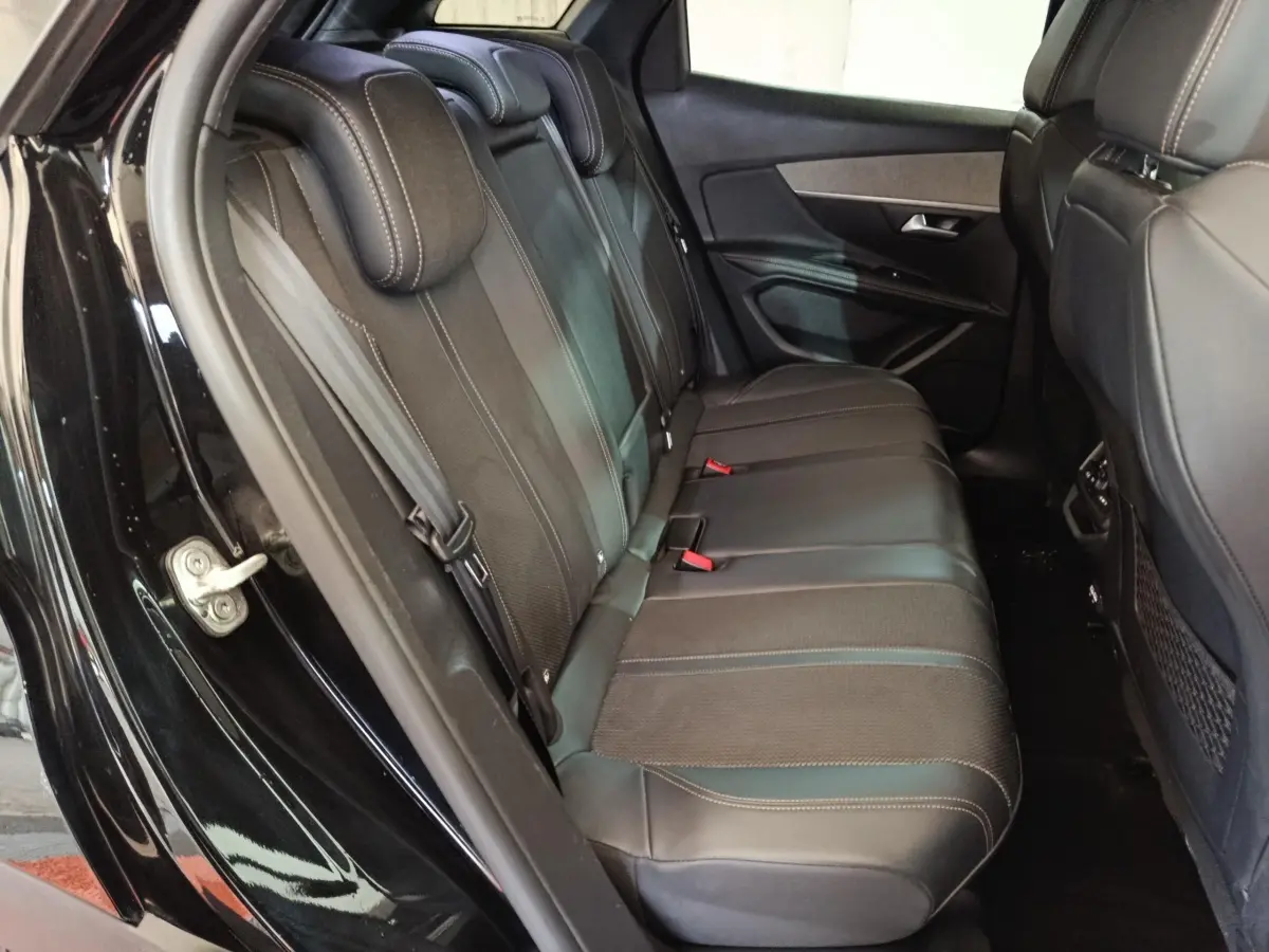 Vue côté gauche des sièges arrière en cuir noir du Peugeot 3008 PureTech 130 GT 2022 avec portières ouvertes.