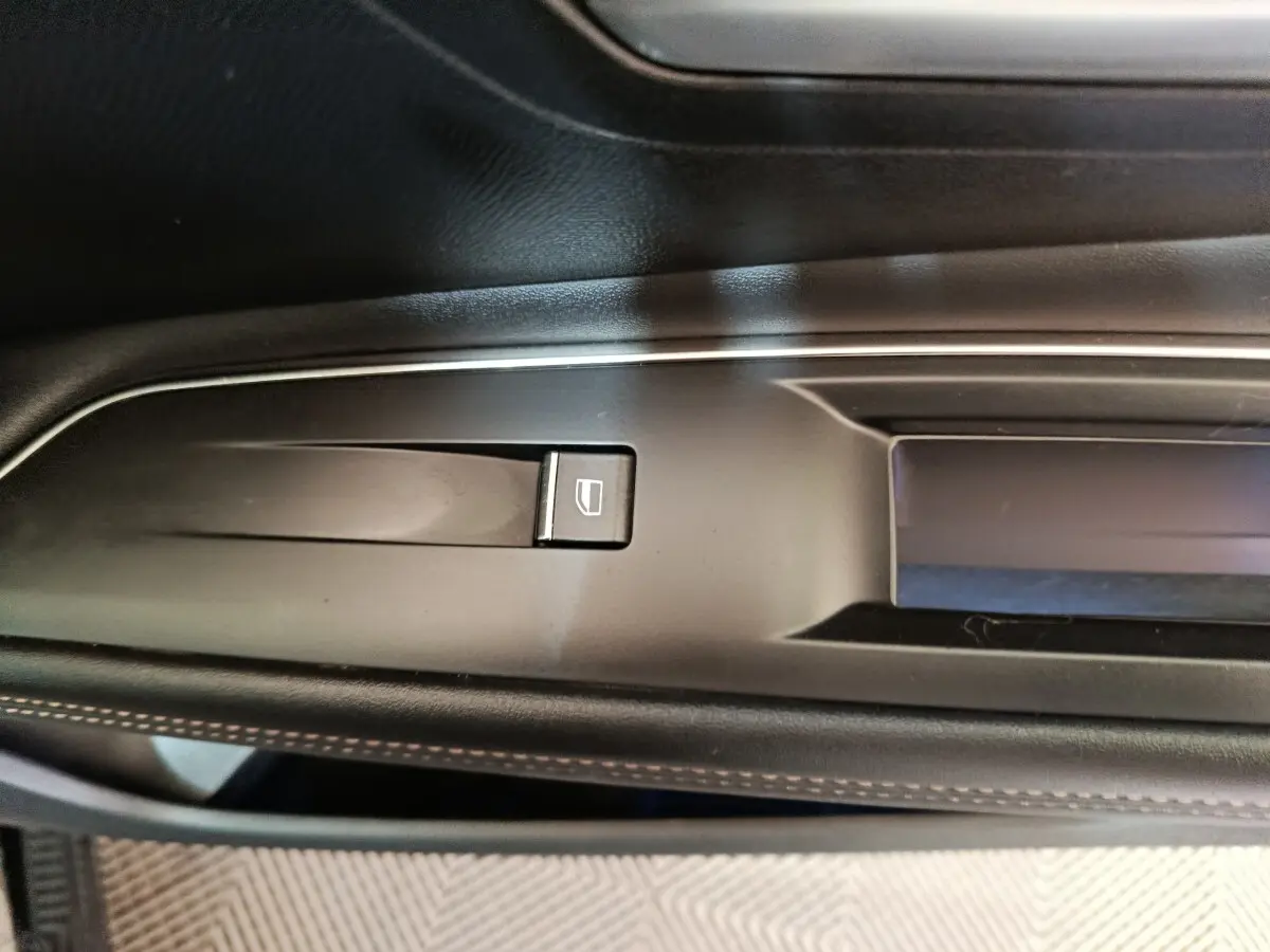 Détail de la commande de lève-vitre sur la porte côté gauche intérieure d’un Peugeot 3008 noir 2022.