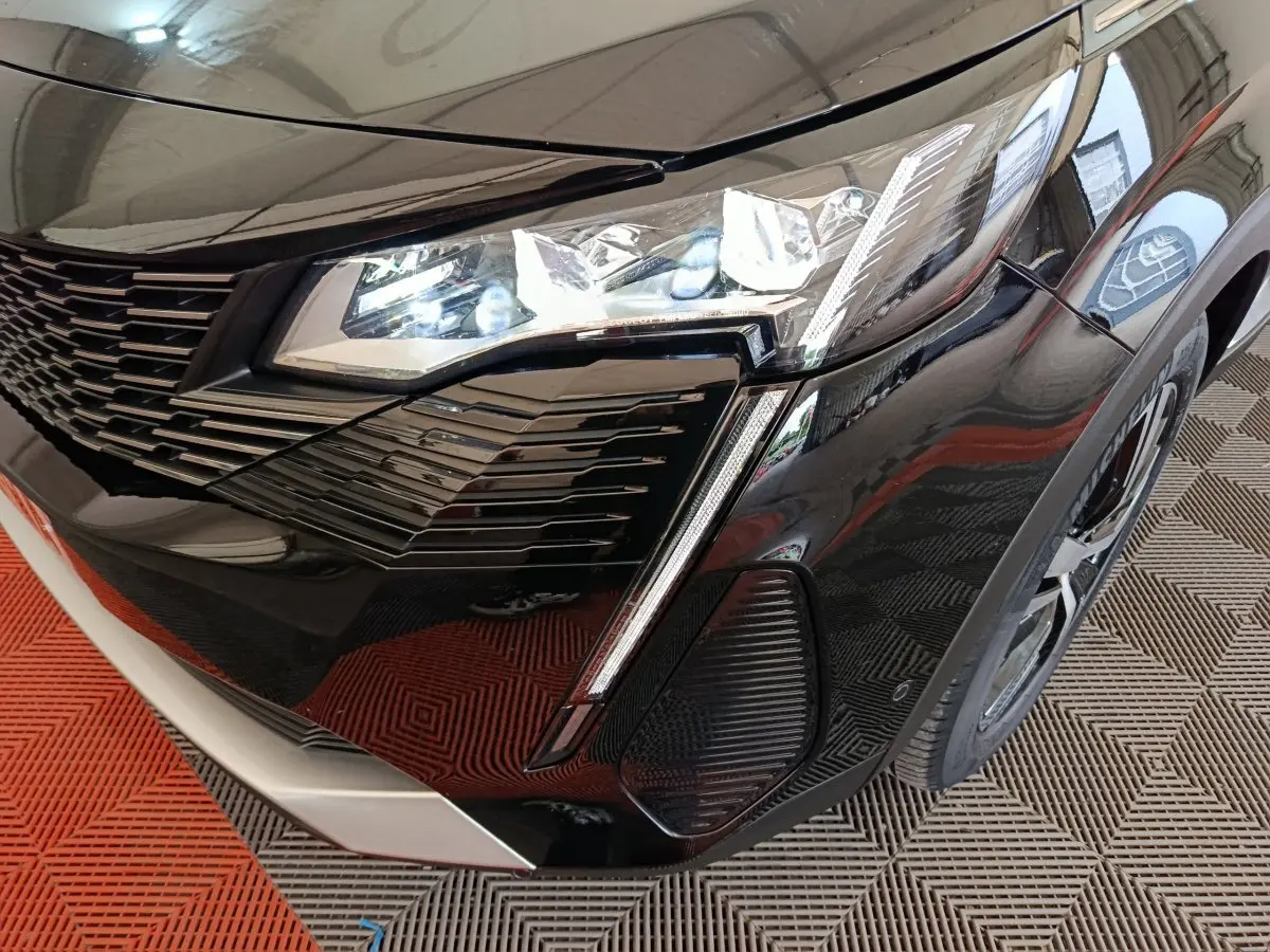 Gros plan sur l'avant droit noir brillant du Peugeot 3008 2022 avec phares LED et calandre distinctive.
