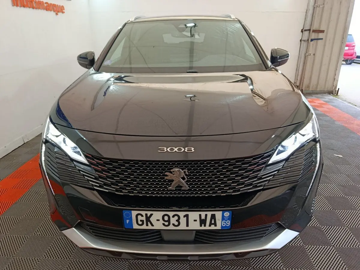 Vue avant d'un Peugeot 3008 noir 2022 avec calandre distinctive et phares LED allumés en intérieur.