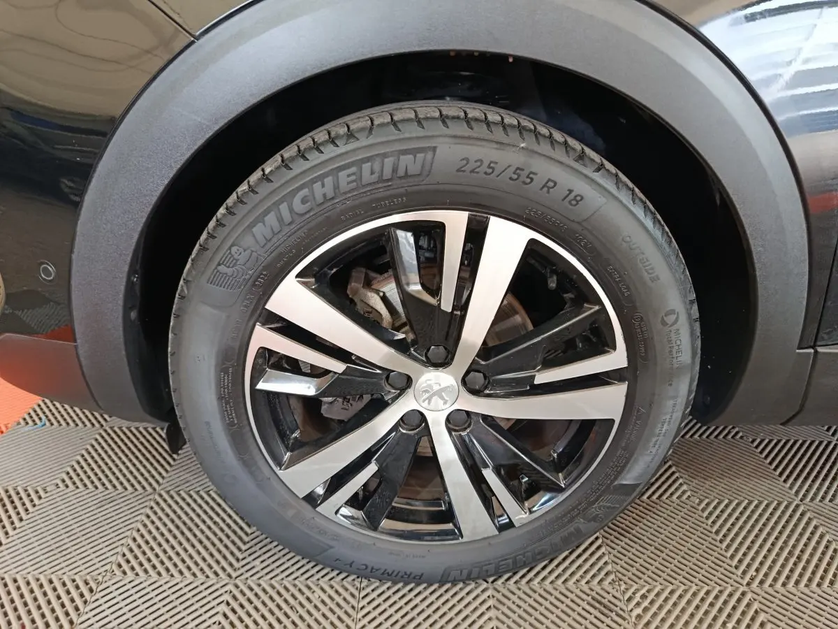 Gros plan sur la roue avant droite noire avec jante alliage bicolore du Peugeot 3008 PureTech 130 GT 2022.