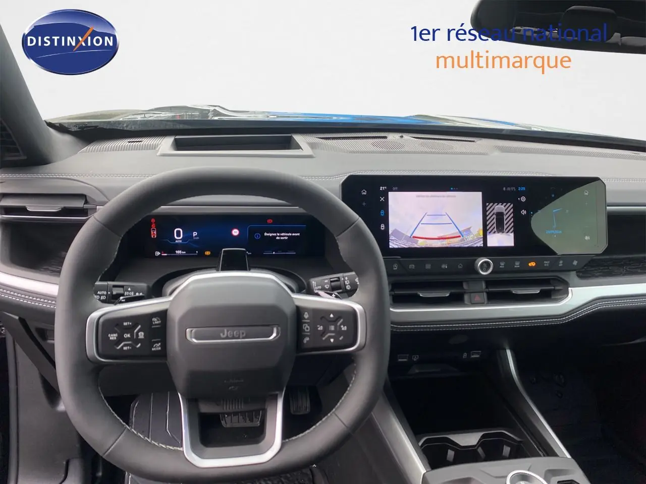 Vue intérieure centrée sur le volant Jeep et le tableau de bord numérique avec écran tactile large, ambiance noire moderne.