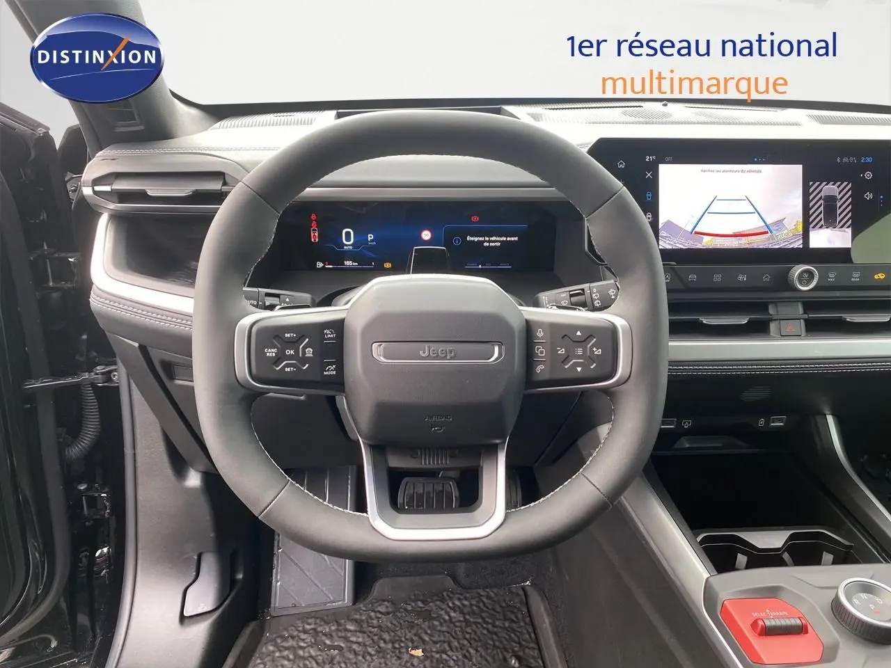 Vue intérieure centrée sur le volant Jeep Compass 2026, tableau de bord numérique et écran multimédia avec caméra de recul.