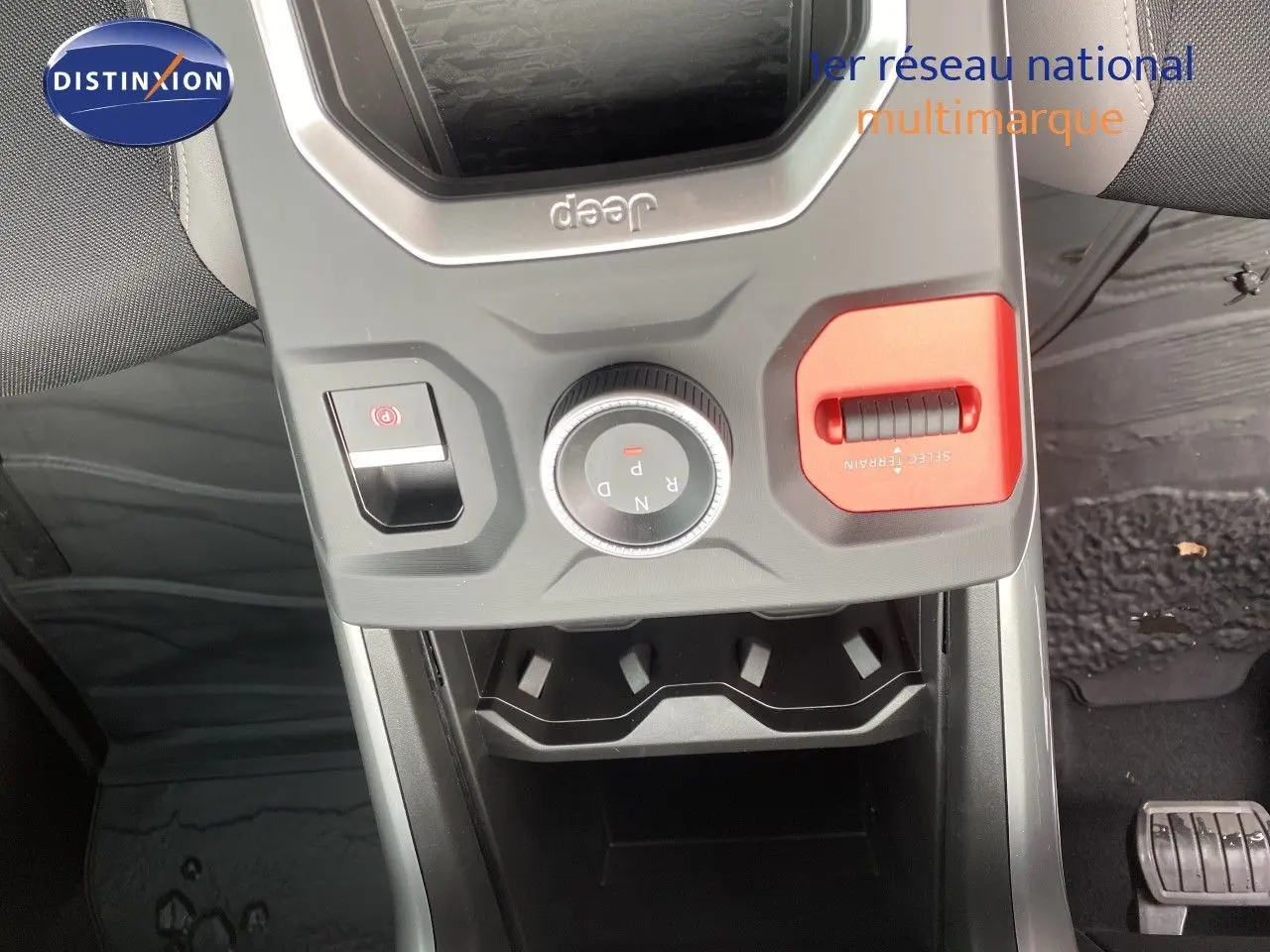 Vue plongeante sur la console centrale du Jeep Compass noir Vulcano, mettant en valeur la molette de boîte auto et le sélecteur terrain rouge.