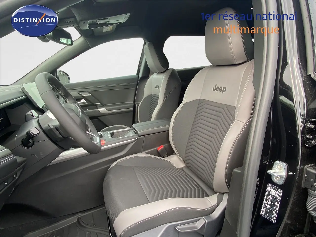 Vue intérieure côté conducteur du Jeep Compass noir Vulcano, sièges bi-ton gris avec logo Jeep brodé sur appuie-tête.