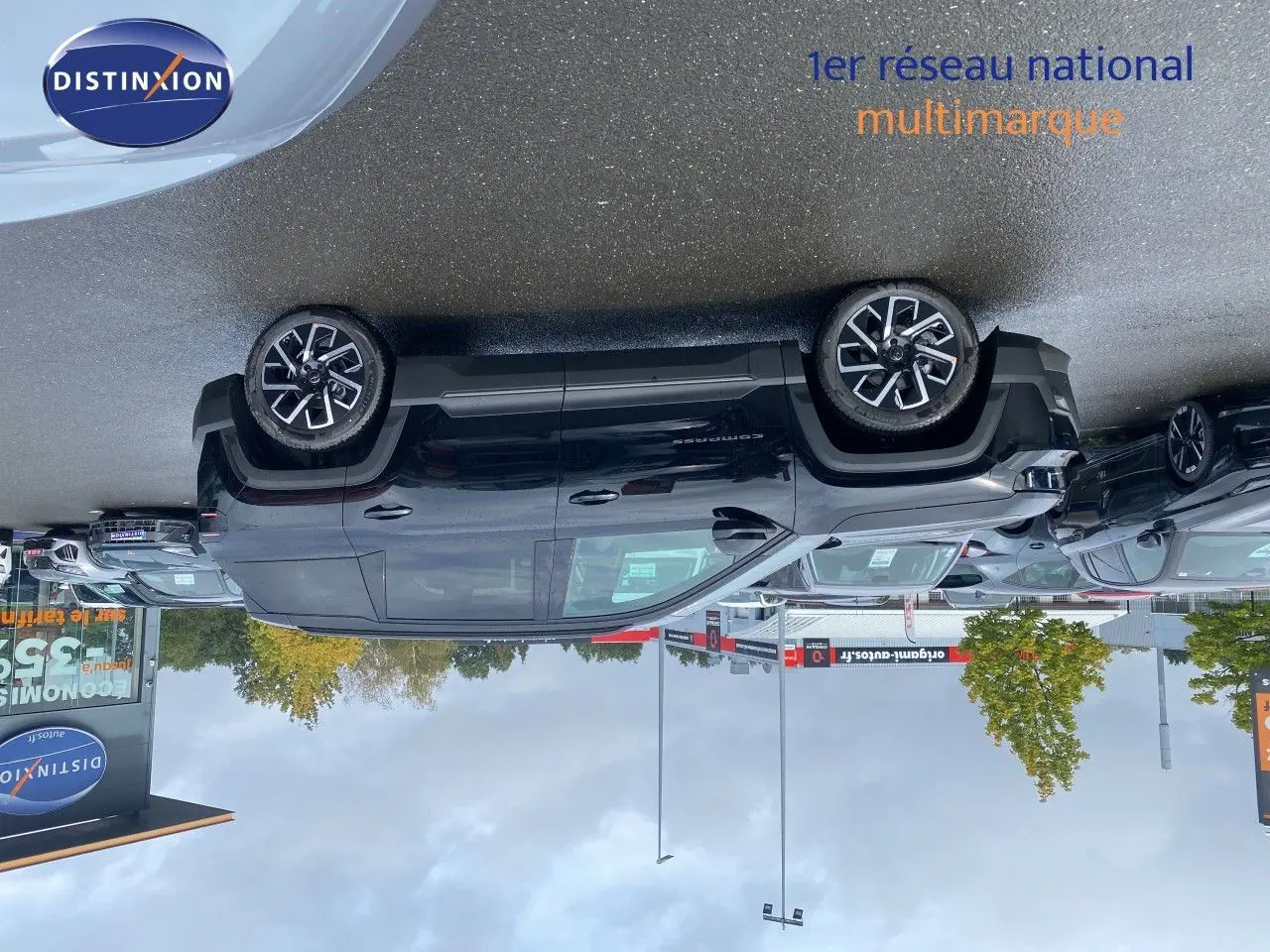Jeep Compass noir Vulcano métal vu de profil côté gauche sur un parking avec plusieurs autres véhicules autour.