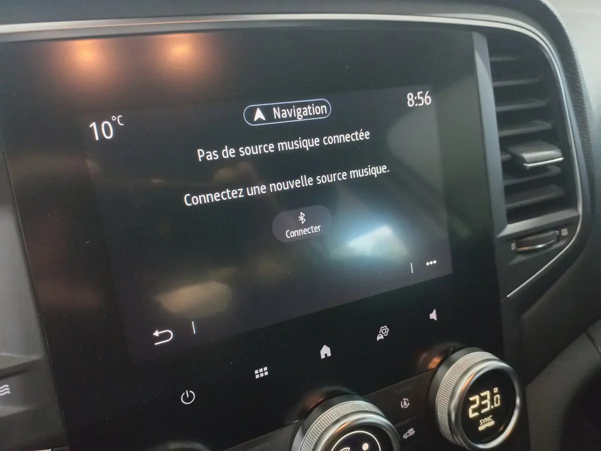 Écran tactile central de la Renault Mégane Business blanc, affichant le menu musique et la température intérieure.